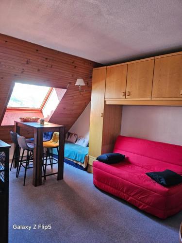 a living room with a red couch and a table at joli studio vue montagne in Allos