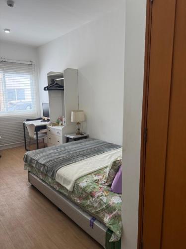 a bedroom with a bed and a desk with a lamp at Bella's Flats in Bayanihan in Pajak