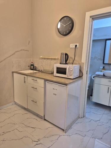 eine Küche mit Mikrowelle und einer Wanduhr in der Unterkunft hotel vital in Rechovot