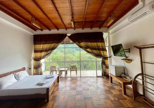 a bedroom with a bed and a large window at Kitulgala Ebony Riverside Resort in Kitulgala