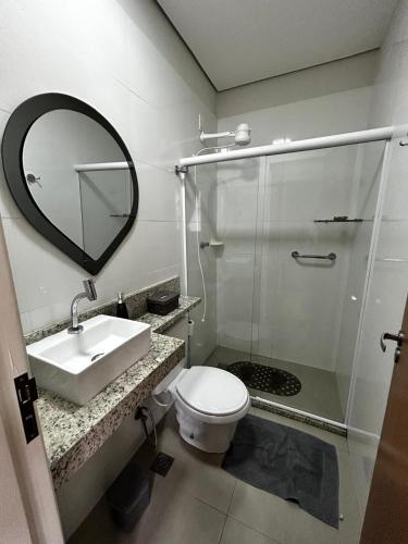 a bathroom with a toilet and a sink and a mirror at Apartamento 1 quarto, sala e cozinha próximo ao Aeroporto in Vitória
