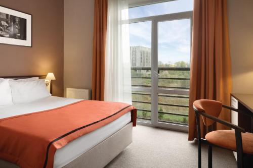 リヴィウにあるLviv Ramada Hotelのベッドと大きな窓が備わるホテルルームです。