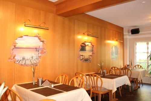 a dining room with tables and chairs in a room with wooden walls at Landhaus Hotel Müller in Ringheim