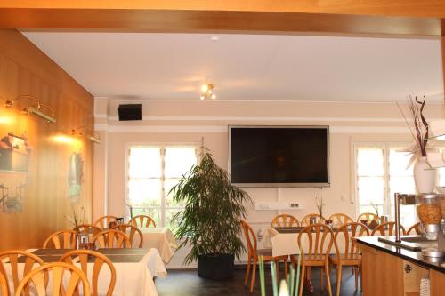 a dining room with a table and chairs and a flat screen tv at Landhaus Hotel Müller in Ringheim