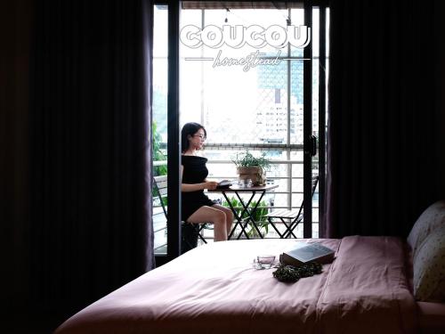 a woman sitting at a table in front of a window at CouCou Homestead II - Mini Hotel District 1 in Ho Chi Minh City