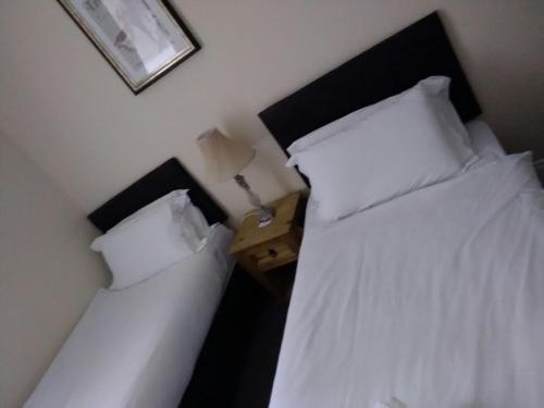 two beds in a bedroom with white sheets and pillows at The Waverley Guest House in Inverness