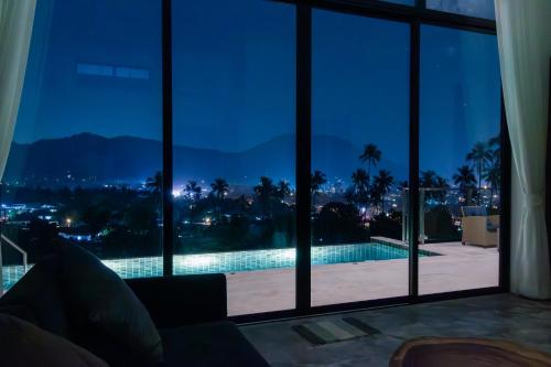 a living room with a view of a swimming pool at night at Panorama View Villa in Ban Thung