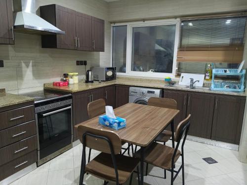 a kitchen with a wooden table and chairs in it at Universe Holiday Homes Burjuman in Sabkhah