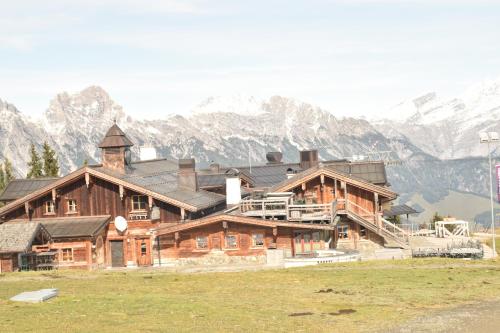 a large wooden house with mountains in the background at Appartement Gassner in Leogang