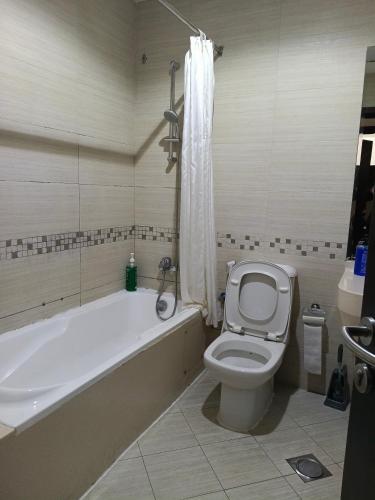 a bathroom with a tub and a toilet and a bath tub at Universe Holiday Homes Burjuman in Sabkhah