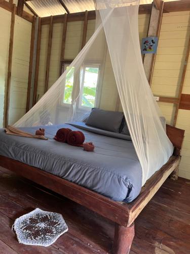 a bed in a room with a mosquito net at Koh Jum Ozone Resort in Ko Jum