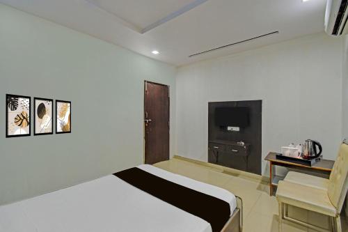 a bedroom with a bed and a desk and a television at Hotel O Madhuram Lodge in Siddipet