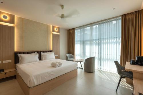 a bedroom with a bed and a desk and a large window at The Continental Suites in Kozhikode