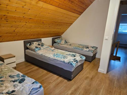 three beds in a room with a wooden ceiling at Domek Bobrowe Zacisze 2 in Karpacz
