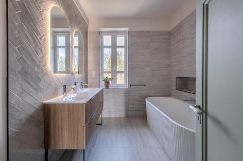 a bathroom with a tub and a sink and a bath tub at La Villa des Coccinelles in Olivet