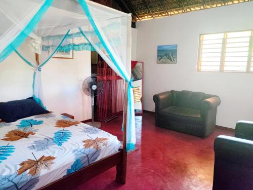 a bedroom with a canopy bed and a couch at Chez Rosa in Nosy Be