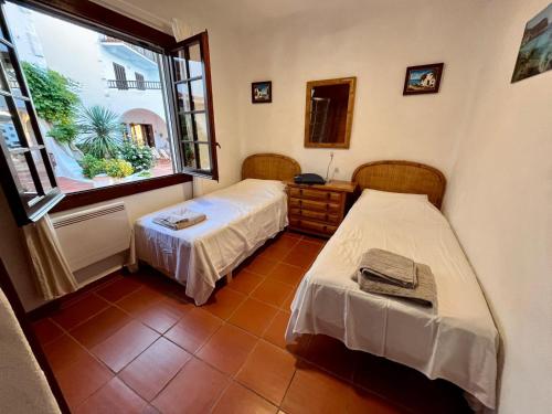 two beds in a room with a window at Casa Cristalina Menorca in Fornells
