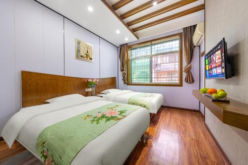 a bedroom with two beds and a television in it at A deer has you INN near by Tianmen Shan--Free pick-up-Aerial Cableway in Zhangjiajie
