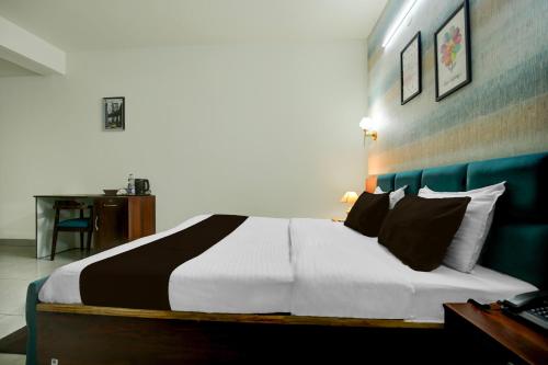 a bedroom with a large white bed with black pillows at Hotel O Riddhinn6 in Jalandhar