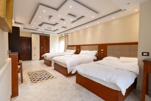 a bedroom with three beds with white sheets at Nilotique in Cairo