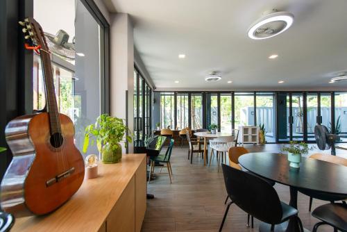 a guitar sitting on the wall in a room with chairs at BB House Rangsit บีบี เฮ้าส์ รังสิต in Ban Talat Rangsit