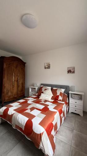 a bedroom with a bed with a red and white comforter at Caprice des Dunes in Notre-Dame-de-Monts