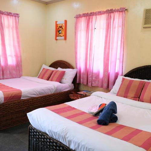 a room with three beds and pink curtains at RR Family Spring Resort in Maramag