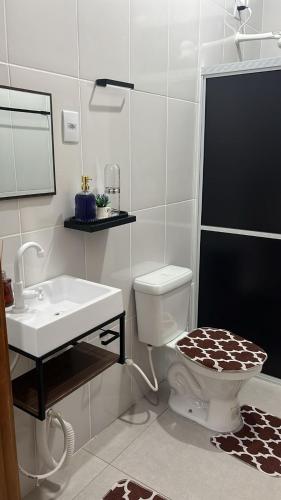 a white bathroom with a toilet and a sink at Apartamento Aconchego II in Alta Floresta
