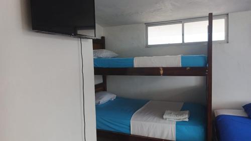 ein Zimmer mit drei Etagenbetten und einem Fernseher in der Unterkunft Hostal Tamara in Manta