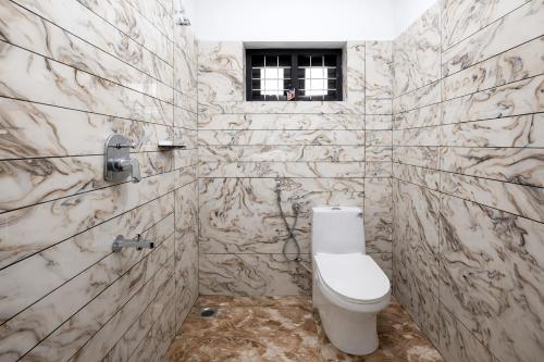 a bathroom with a toilet and a window at Varkalite homestay in Varkala