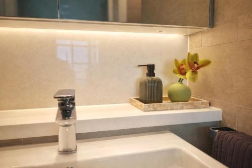 a bathroom sink with a faucet and a vase with flowers at Sleeps 6 Dreamy Designer Apt Wintergarden Dining 1min to Stadium & Free Parking in Sydney