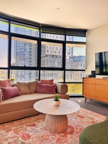 a living room with a couch and a table at Sleeps 6 Dreamy Designer Apt Wintergarden Dining 1min to Stadium & Free Parking in Sydney