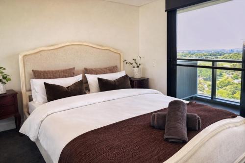 a bedroom with a large bed with a large window at Sleeps 6 Dreamy Designer Apt Wintergarden Dining 1min to Stadium & Free Parking in Sydney