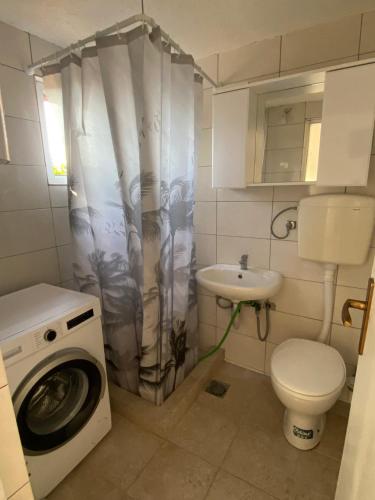 a small bathroom with a washing machine and a sink at Pink Holiday House Sutomore in Zankovići