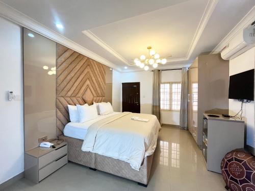 a bedroom with a large bed and a flat screen tv at Deluxe Indulgence Hotel & Suites in Abuja
