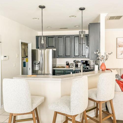 a kitchen with white cabinets and a counter with chairs at Spacious Private 2BR-2BA I Pool I Garage I Central in Rehoboth Beach