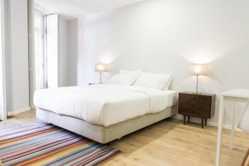 a white bedroom with a large bed and a table at Porto República Suites in Porto