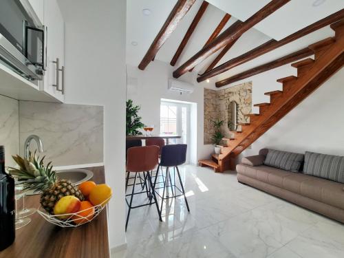 a kitchen and living room with a couch and a bowl of fruit at AURA Apartments Novalja in Novalja