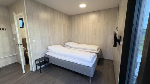 a small room with a bed with white sheets at Tommutún cottages in Borgarnes