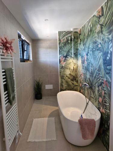 a bathroom with a tub and a tropical mural at Villa Atma in Murine