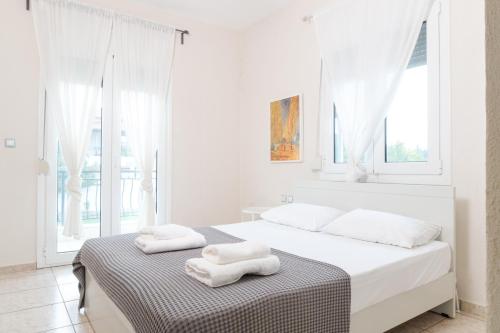 a white bedroom with two white towels on a bed at Dimeli 1 in Plaka Litochorou