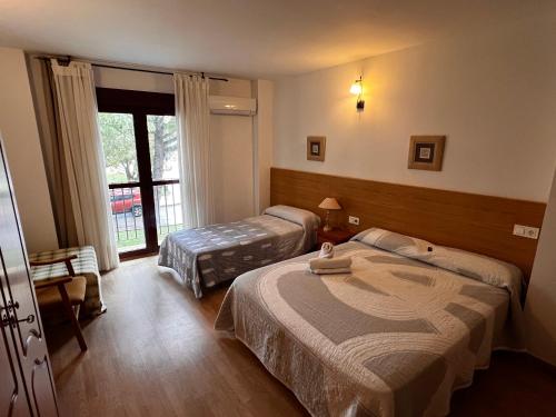 a hotel room with two beds and a window at Hotel Puente de Piedra in Zamora