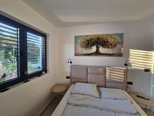 a bedroom with a bed and a tree painting on the wall at Villa Atma in Murine