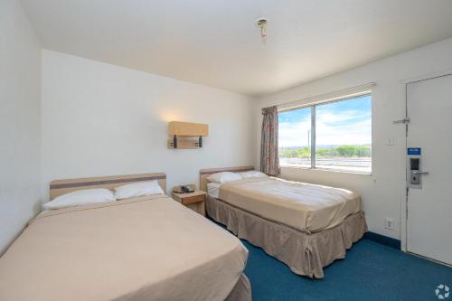 two beds in a room with a window at Gazelle Stay by Hotel O Socorro in Socorro