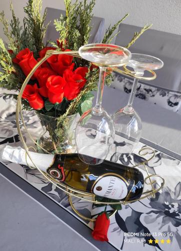 a tray with two wine glasses and a vase of roses at Apartment Mali Raj -Stunning Gacka River View-Peaceful Nature Escape in Otočac