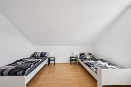 two beds in a room with white walls and wooden floors at Cosy Worker Apartment Olpe in Olpe