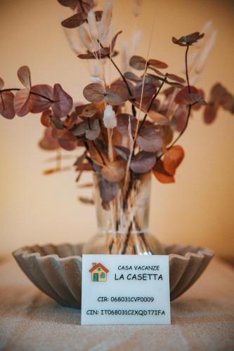 a vase with flowers in it on a table with a plate at La Casetta - un piccolo angolo di pace in Piccianello