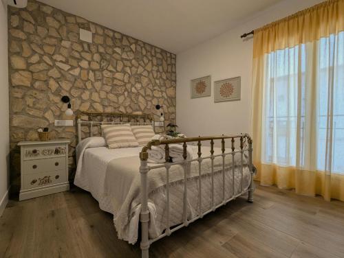 un dormitorio con una cama y una pared de piedra en Casa Cisca, en Quesada
