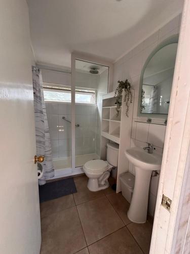 a white bathroom with a toilet and a sink at De Peppino Cabañas in Papudo