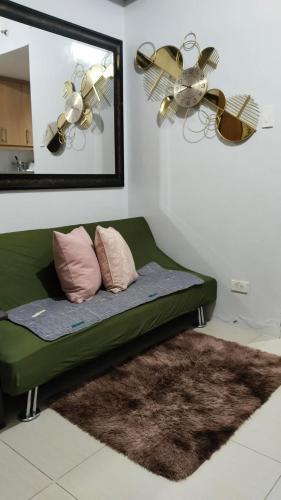 a green couch in a room with a mirror at Nygel Staycation at Shell Residences in Sampong